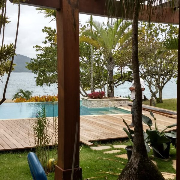 Deck, piscina e jardim tropical beira mar